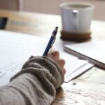 finanzielle Unabhängigkeit — offenes Notizbuch mit handschriftlicher Planung neben Stift